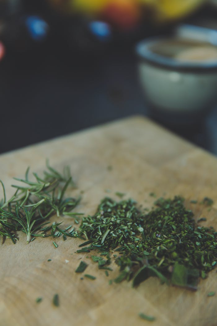 Chopped fresh rosemary herbs on a wooden board, ideal for cooking and culinary themes.